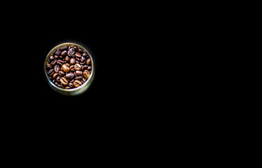 Coffee beans in glass cup. Placed on the black background.