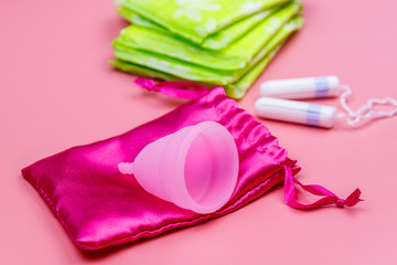 Sanitary pad, tampons and menstrual cup on pink background. Concept of critical days, menstruation, feminine hygiene