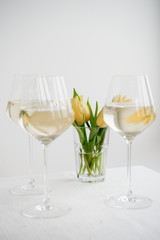 White wine. Dry wine. Glass of wine on the backgound table. Spring flowers. Yellow tulips.