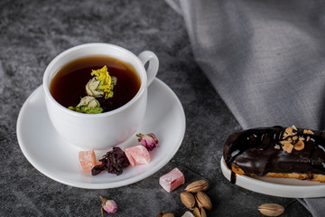 A cup of tea with Turkish lokum and chocolate eclair. top view