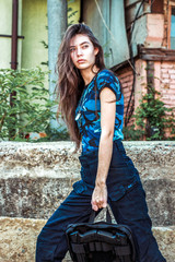 Girl in tactical clothes with a gun. Military woman. Blue camouflage T-shirt and bag with two pistols. Civilian clothing.