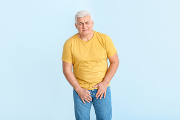 Mature man with urologic disease on color background