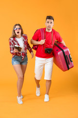 Worried couple of tourists with luggage on color background