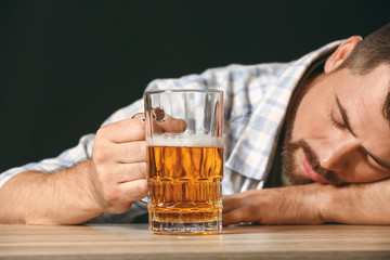 Drunk man with beer at table. Concept of alcoholism