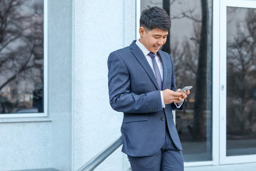 Young Asian businessman with mobile phone outdoors