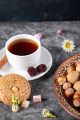 A cup of tea with cookies and nuts on the table
