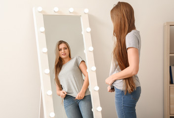 Displeased young woman near mirror at home