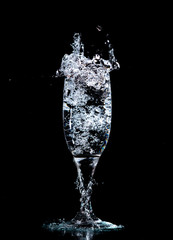 Water with splashes in a glass on a black background