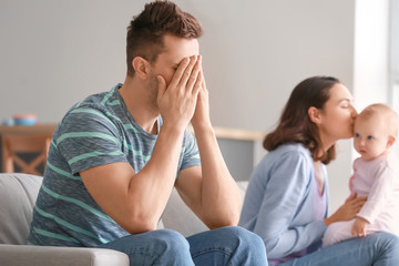 Happy mother with her baby and young father suffering from postnatal depression at home