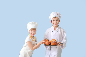 Cute little chefs with pastry on color background
