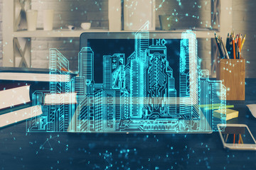 Desktop computer background in office and big town buildings hologram drawing. Double exposure. Smart city concept.