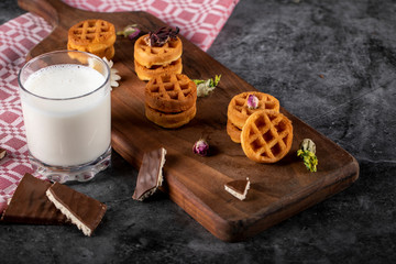 Waffles on a wooden board with a cup of milk. top view