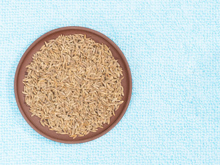 Cumin (jeera) in clay plate on blue fabric background