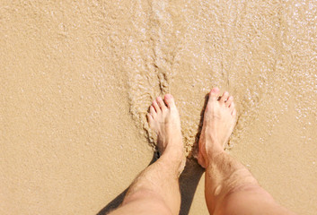 Feet of a man in the hot sand of the desert