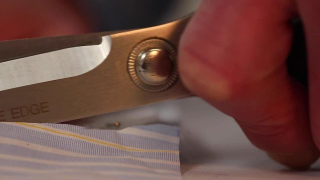 Extreme close up of scissors cutting cloth. Following a pattern for a striped shirt