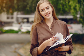 Beautiful girl studies. Student use the notebook. Lady in a summer park