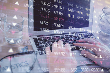 Multi exposure of market chart with man working on computer on background. Concept of financial...