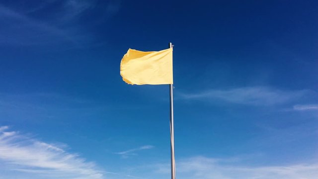 Small yellow flag waving against blue sky