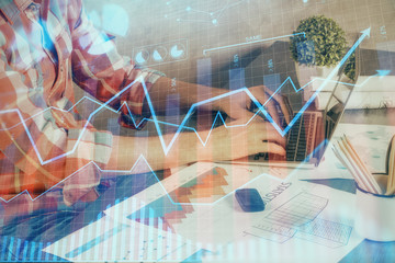 Double exposure of stock graph with businessman typing on computer in office on background. Concept...