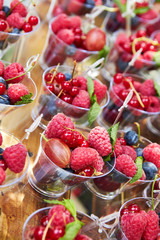 Cups with fresh berries in summer garden.