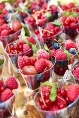 Cups with fresh berries in summer garden.