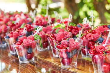 Cups with fresh berries in summer garden.