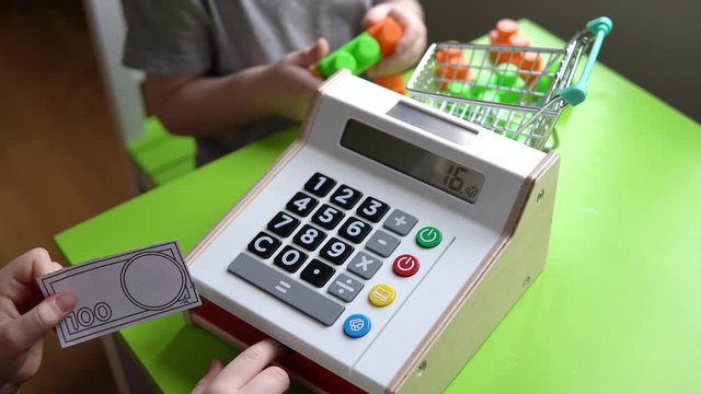 Kids playing shop with toy cash register and money, learning numbers, children shopping, selling, buying.