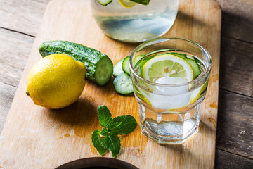 Fresh water with lemon, mint and cucumber on wooden background