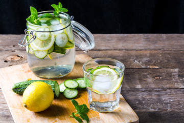 Fresh water with lemon, mint and cucumber on wooden table