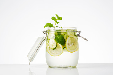Detox water with lemon and cucumbers in jar on white background