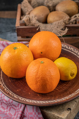 Lemon and oranges in a brown pottery saucer
