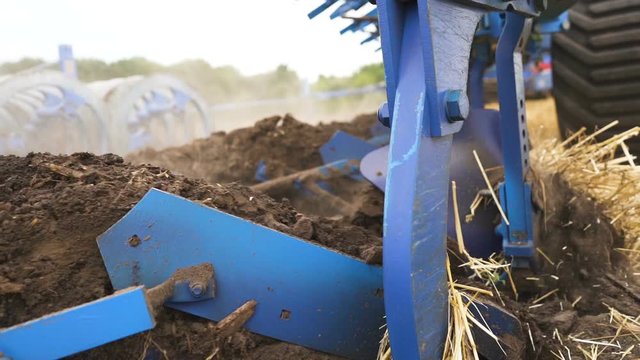 Agriculture industry team .Plow plows earth in field, steady shot, close up, slow motion