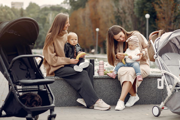 Mothers with children. Women use the carriages. Family sitting in a park
