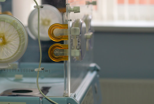 Empty Infant Incubator In An Hospital Room. Closeup View Of Nursery Incubator For Newborn. Box For Carrying Premature Babies.