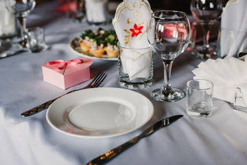set of empty glasses and plates with Cutlery on a white tablecloth on the table in the restaurant