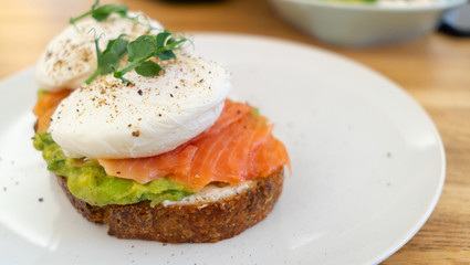 Healthy food. Sandwich with fish: coarse-grained bread, cream cheese, guacomolli cheese, salmon, poached egg, greens. Ready to eat.