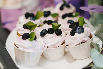 Sweet homemade cupcakes with blueberries and blackberries and white cream