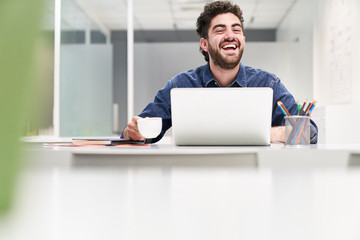 Lachender Student oder Entrepreneur am Laptop