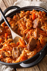 stewed cabbage with meat, tomatoes, carrots closeup in a plate. vertical