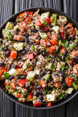 Mexican salad of quinoa, avocado, peppers, tomatoes and black beans close-up in a plate. Vertical top view