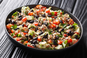 Dietary fitness salad of quinoa, avocado, pepper, tomatoes and black beans close-up in a plate. horizontal