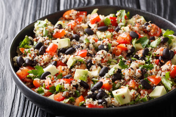 Vegetarian quinoa salad with fresh avocado, peppers, tomatoes and black beans close-up in a plate. horizontal