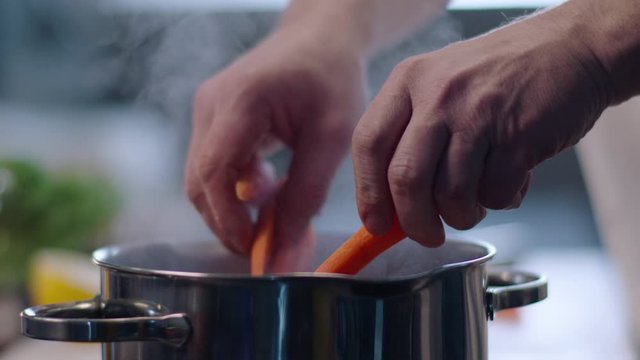 man cooking carrots in kitchen