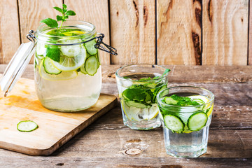 Fresh water with lemon, mint and cucumber on wooden table