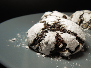 Homemade chocolate cookies. Chocolate brownie cookies in powdered sugar in black background. Selective focus.
