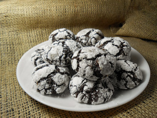 Homemade chocolate cookies. Chocolate brownie cookies in powdered sugar in burlap background. Selective focus.