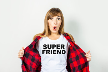 Young woman with a surprised face in a red shirt on a white background. Super friend text added on t-shirt. Concept for text, logo, shock, surprise. Banner