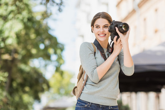 Woman professional photographer with dslr camera outdoors portrait. Pretty young girl in the city taking images with photo camera