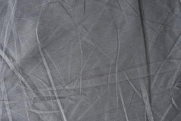 Abstract pattern of a gray crumpled bed sheet in bedroom. Gray wrinkled fabric texture rippled surface, Close up bed sheet in the bedroom.