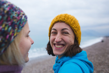 Two smiling girls hug each other on the beach.